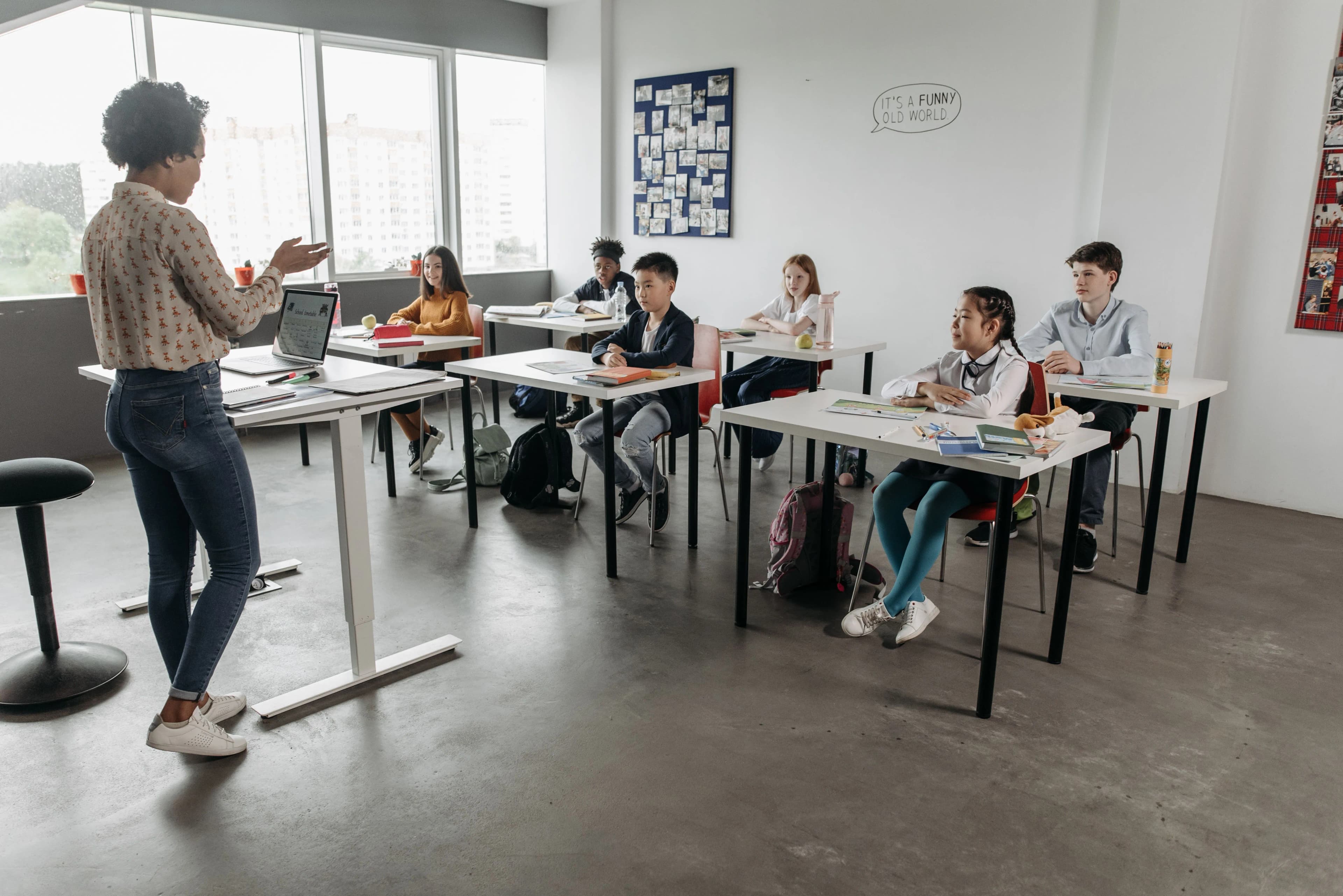 Une enseignante debout s’adresse à une classe de lycéens assis à leurs tables pendant un cours.