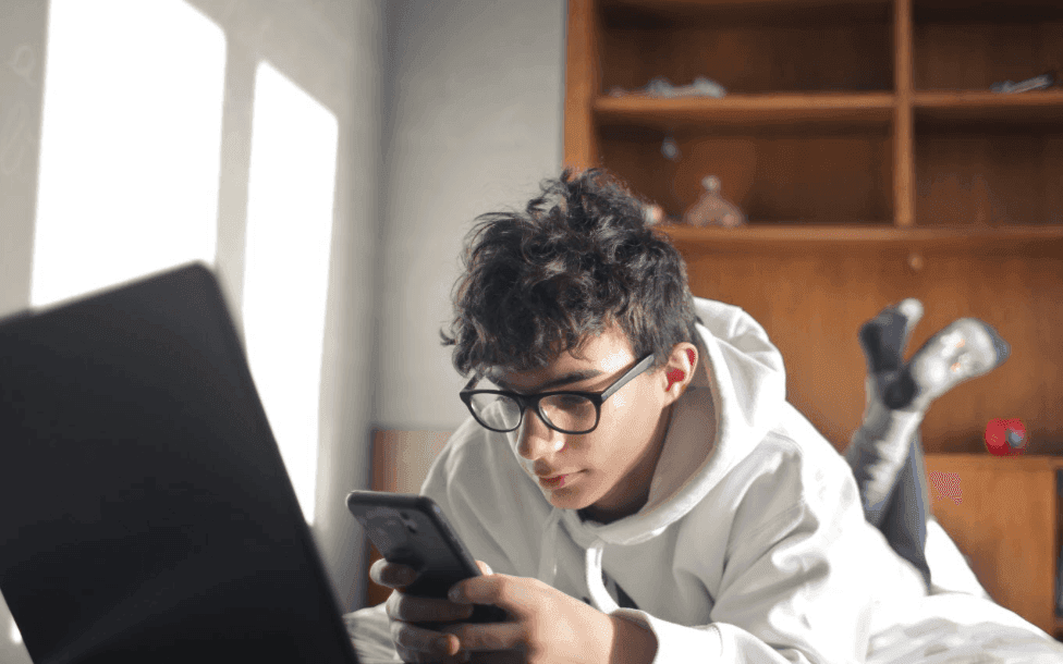 un ado lisant un article ayant comme titre : Orientation scolaire : aider votre ado à réduire son temps d’écran pendant les révisions du bac