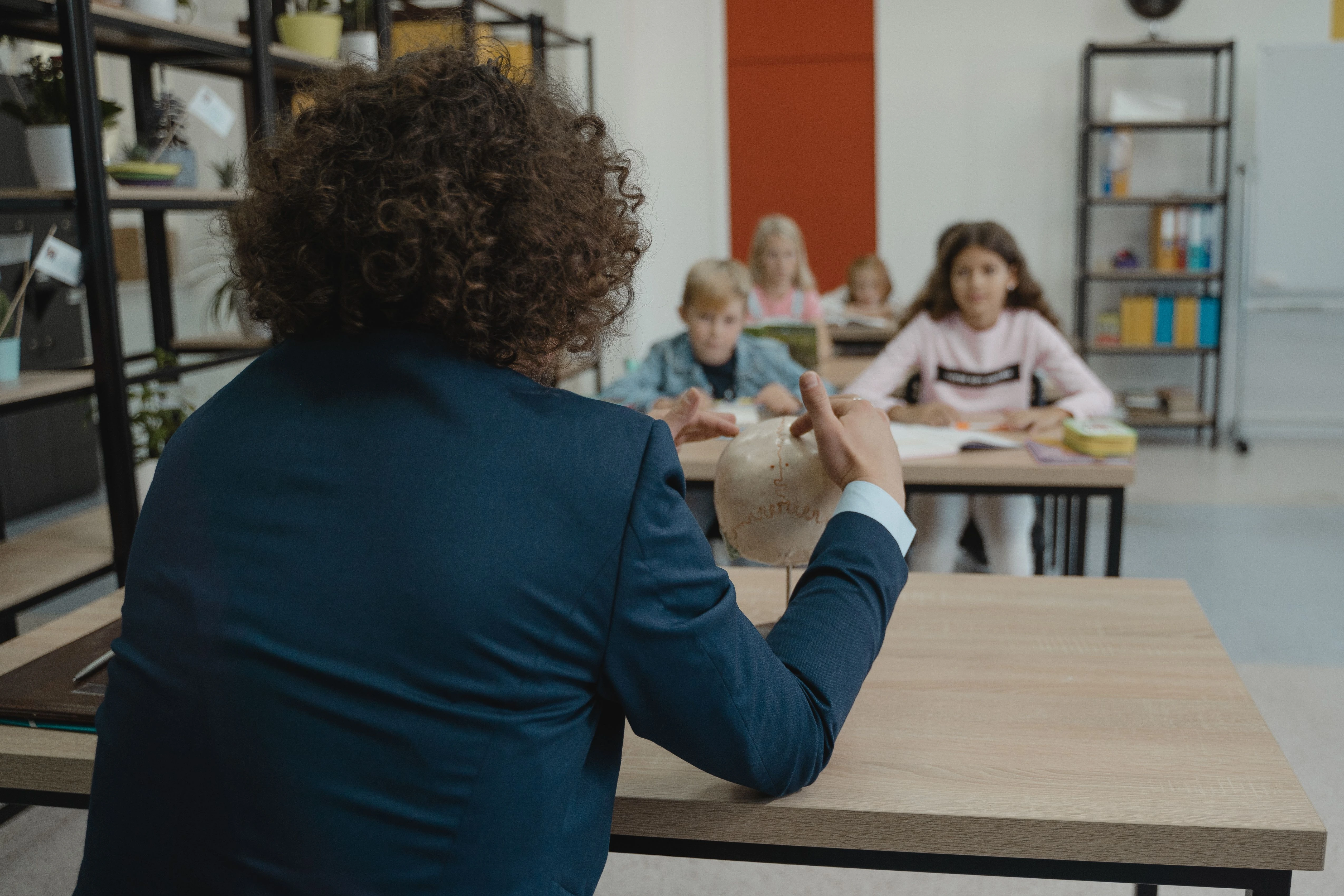 Un enseignant explique un cours à l’aide d’un modèle anatomique face à des élèves attentifs.
